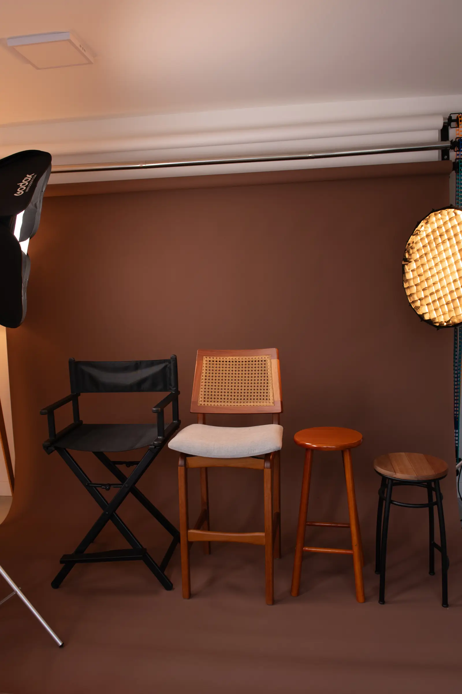 Fundo marrom do estúdio com cadeira de diretor, banquetas de madeira e iluminação profissional