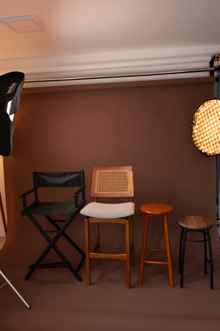 Fundo marrom do estúdio com cadeira de diretor, banquetas de madeira e iluminação profissional