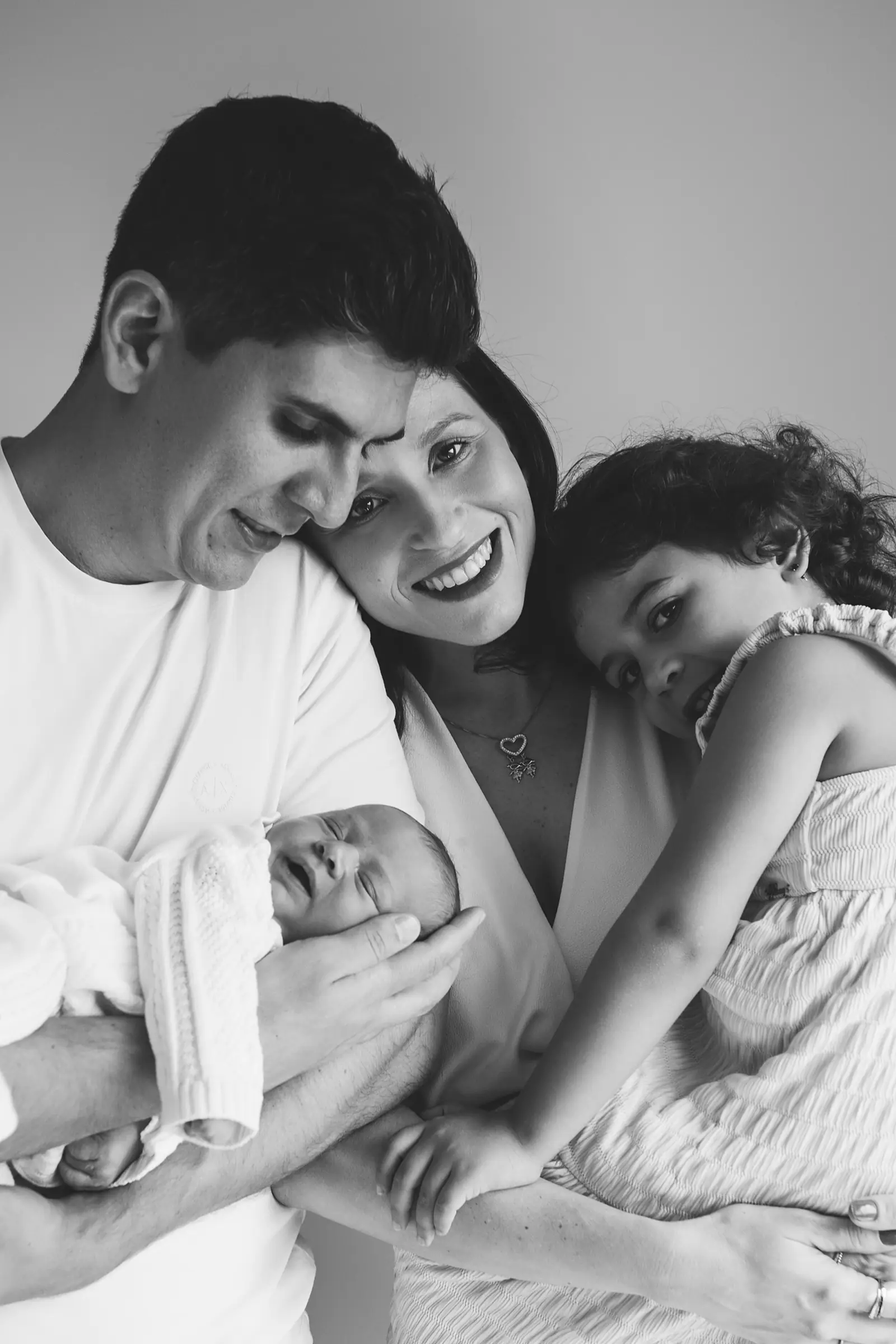 Pai, mãe e filha mais velha com bebê no colo, preto e branco