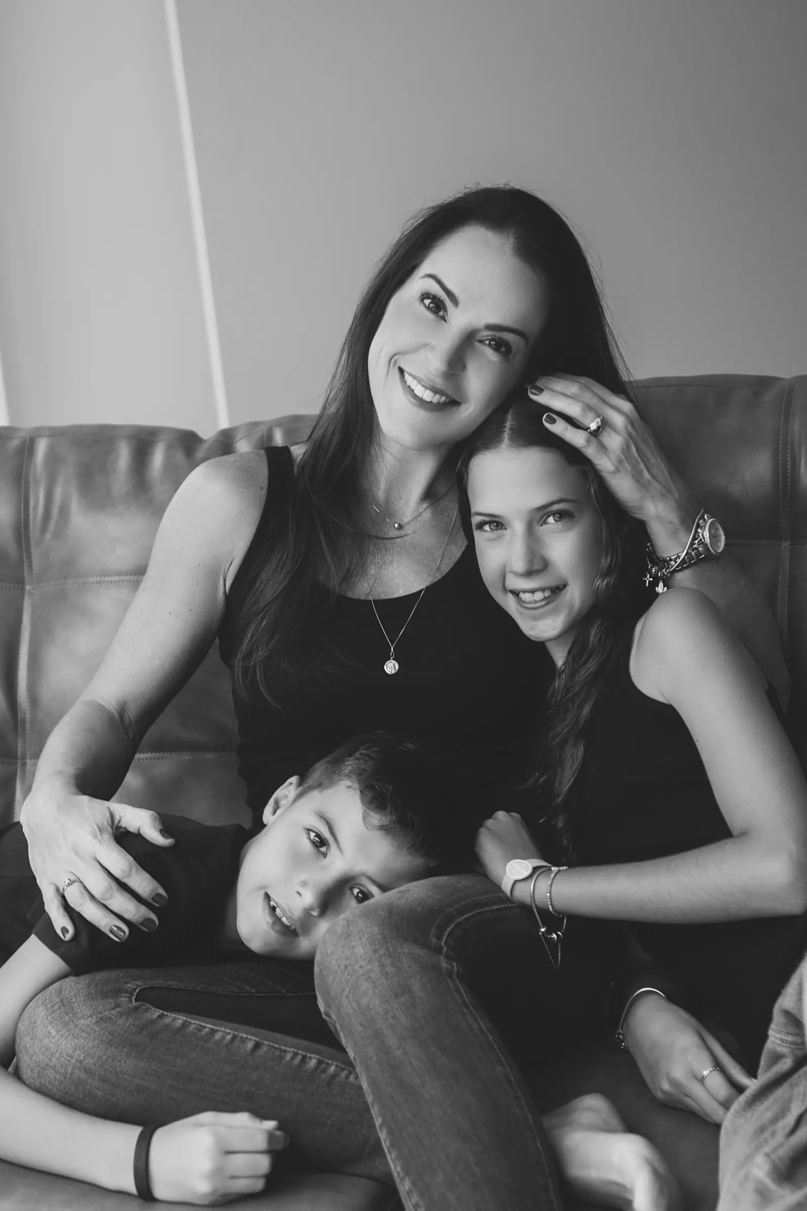 Mãe com a filha adolescente e o filho pequeno no sofá, preto e branco