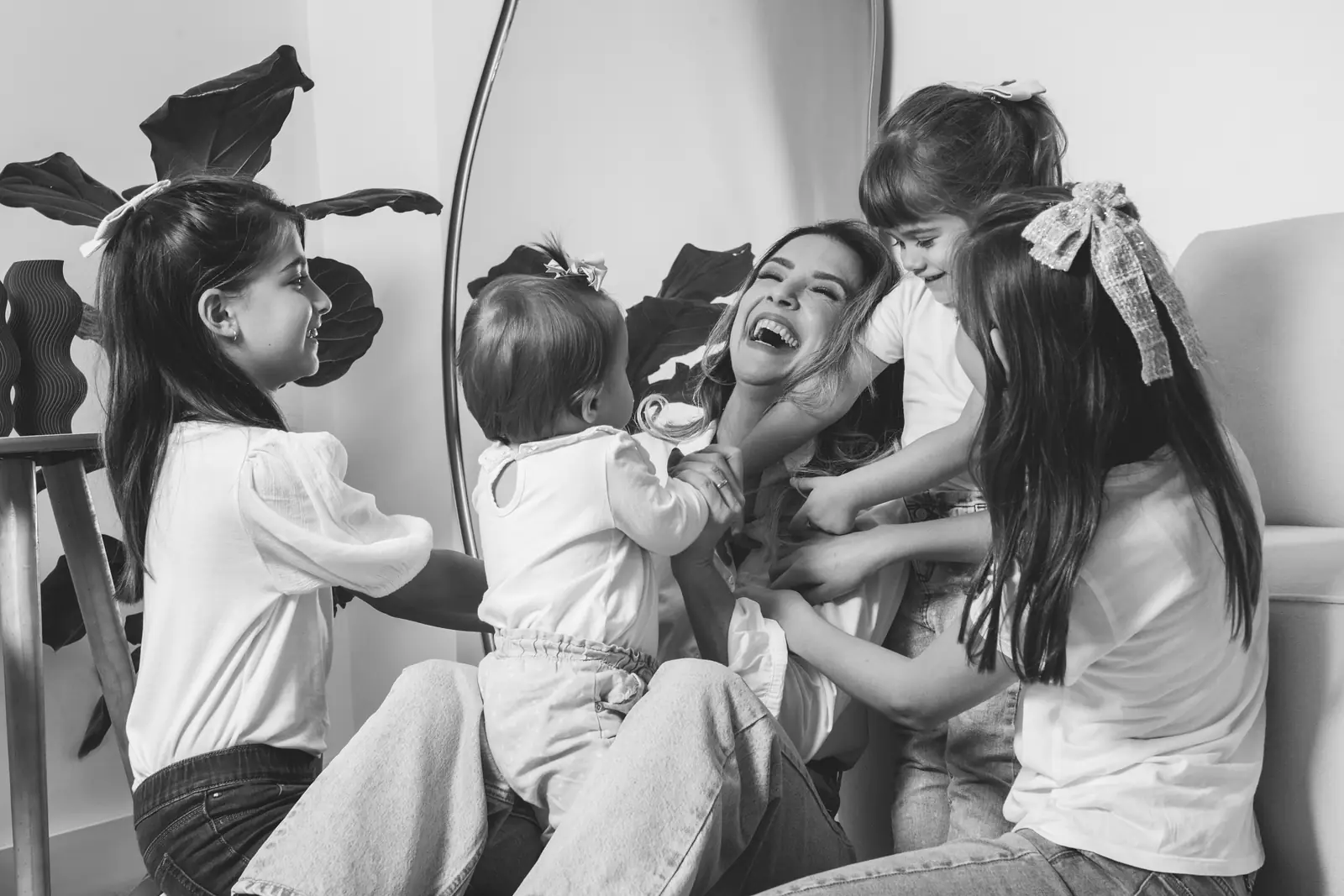 Mãe rindo com as duas filhas pequenas, reflexo no espelho, preto e branco