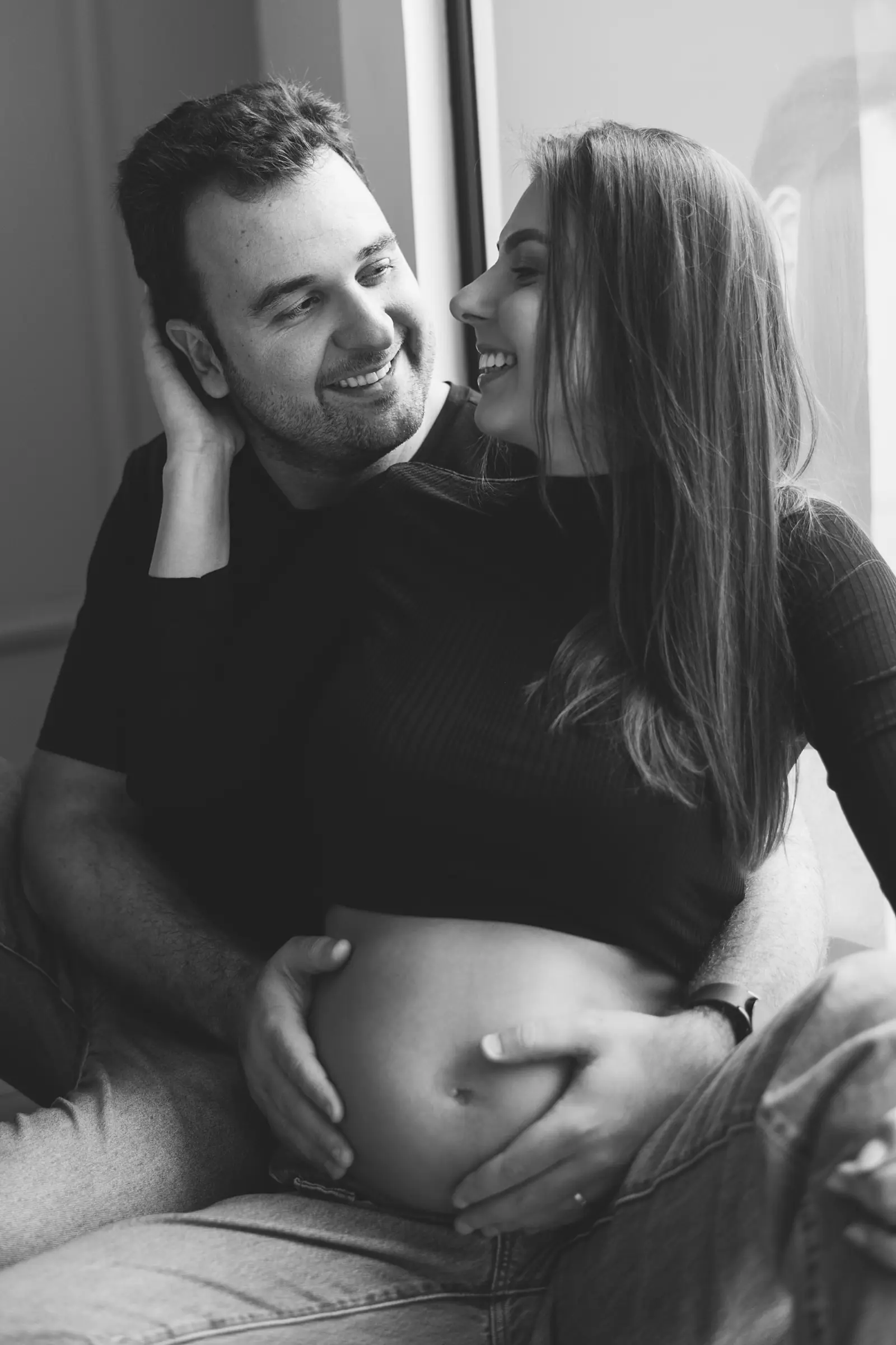 Casal rindo com as duas mãos sobre a barriga, preto e branco
